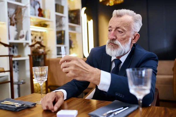 画像老人灰白的头发坐在餐馆里看电子香烟 — 图库照片