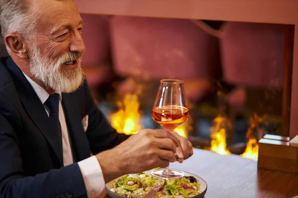 Senior elegant man with glass of red wine in restaurant