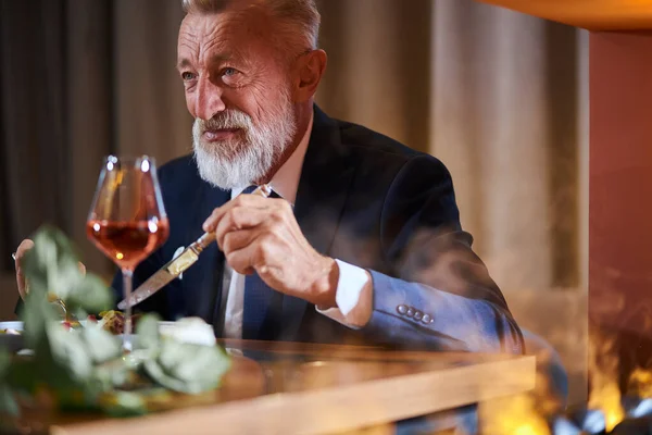 Volwassen zakenman zittend in elegant restaurant en champagne drinkend — Stockfoto