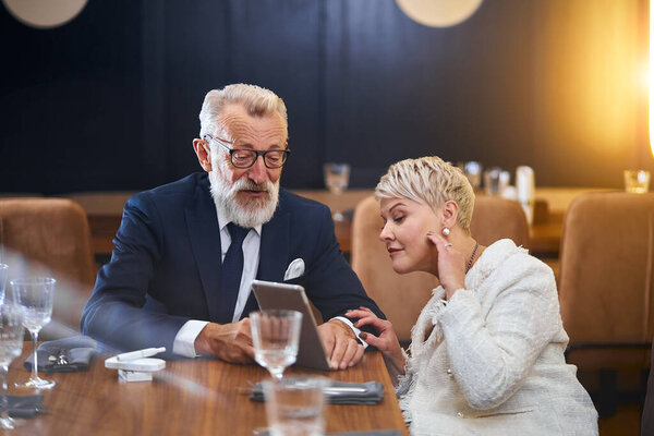 Portrait of cheerful senior couple on date, with laptop in hands chat and enjoy