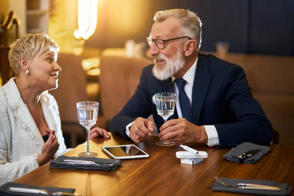 Привлекательная пожилая пара, сидящая за столом ресторана и разговаривающая — стоковое фото
