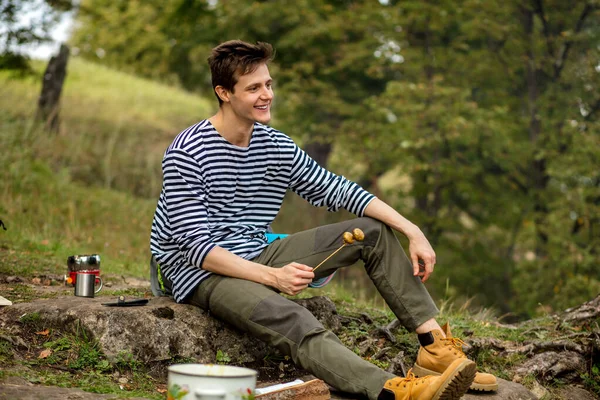 Happy guy sitting on the wood cooking mushroom — Stock Photo, Image