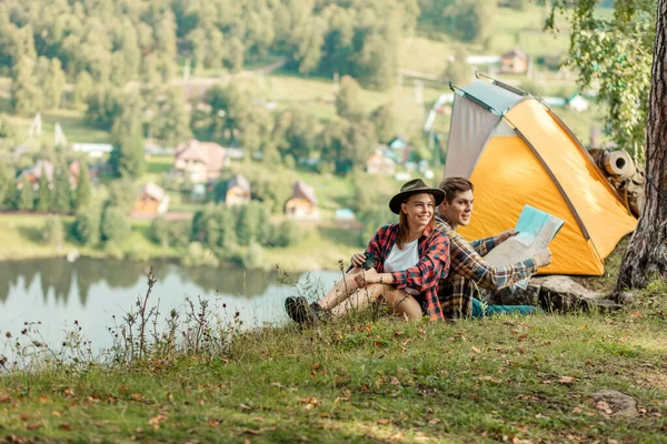 Boldog fiatal férfi és nő ül a fűben, élvezi a vidéki élet — Stock Fotó