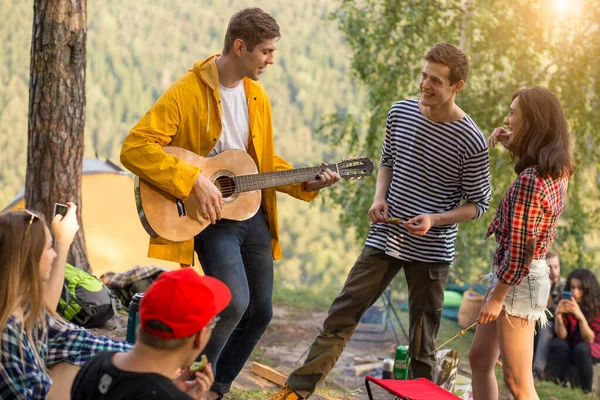 Young funny guy performing his song to a friends while resting outdoors — Stock Photo, Image