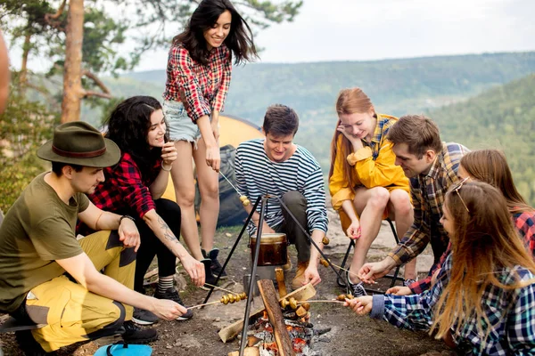 Giovani escursionisti felici che cucinano funghi sul fuoco — Foto Stock
