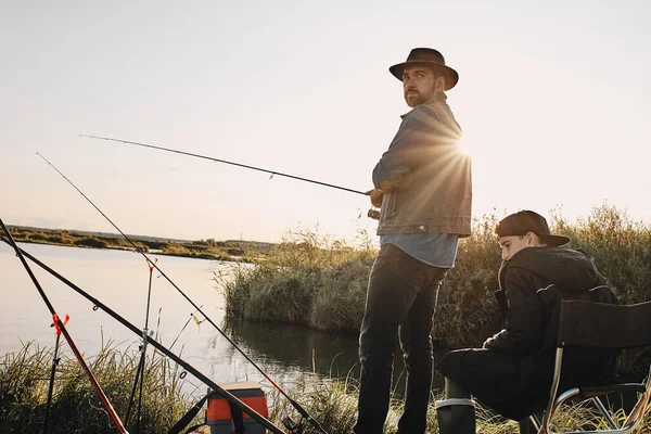 Father and son fishing together on sunny day