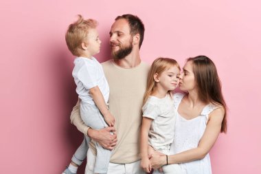 Genç baba ve anne çocuklarını öpüyor.