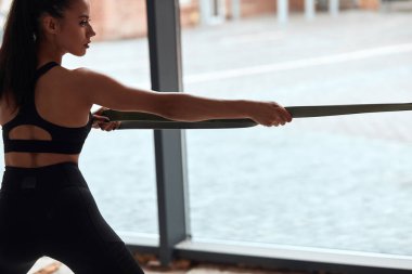Spor salonundaki beyaz atletik kadın vücut geliştirici elastik ip egzersizleri yapıyor.