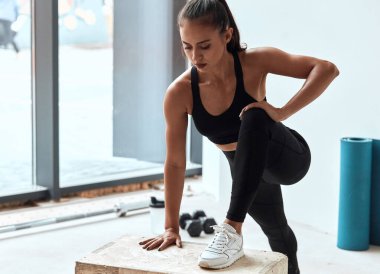 Güçlü ve sportif bir kadın formda bir kutuya yaslanıyor.