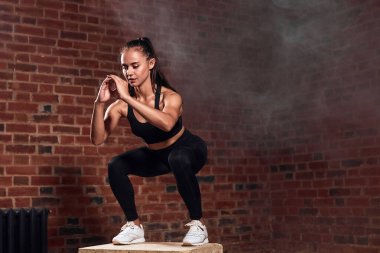 Güzel kadın vücut geliştirici spor salonundaki formda bir kutuya atlıyor.