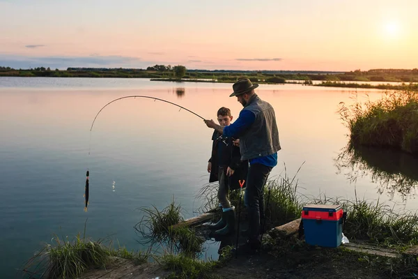 A primeira pesca conjunta de pai adulto e filho adolescente em dia quente e ensolarado . — Fotografia de Stock