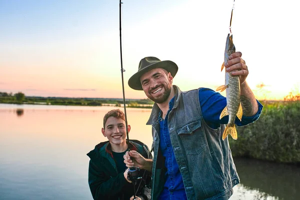 La prima pesca congiunta di padre adulto e figlio adolescente in giornata calda e soleggiata . — Foto Stock