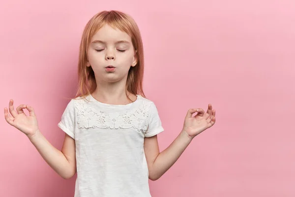 Liten avslappnad söt flicka utövar yoga, isolerad på rosa — Stockfoto