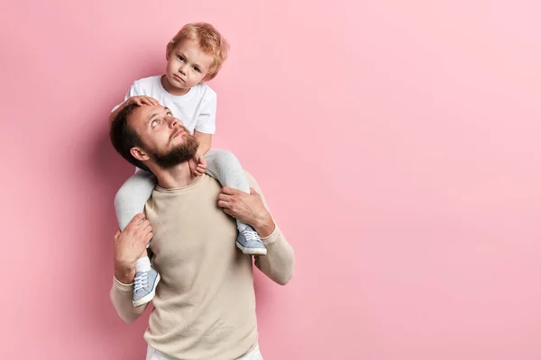 sad unhappy boy sitting on the shoulder of his dad father looking at him