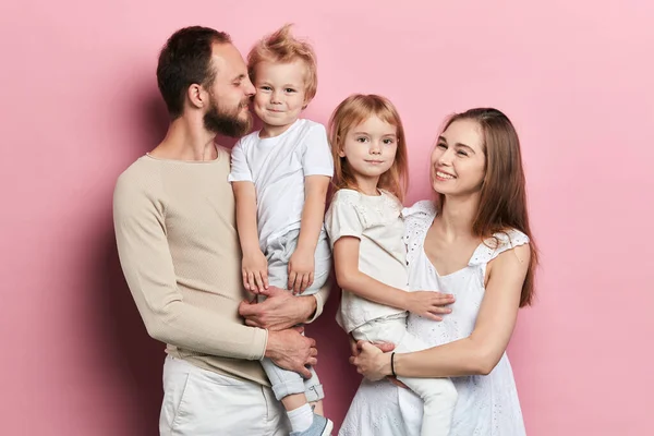 Jovem família feliz com adoravle filhinhas posando no fundo rosa — Fotografia de Stock