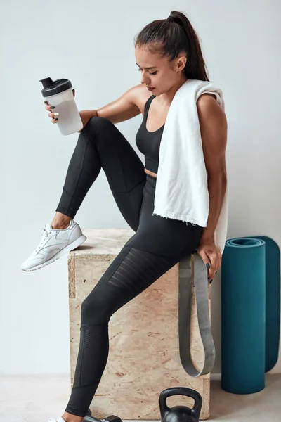 Hermosa mujer bebiendo un poco de agua de botella de plástico después de la aptitud — Foto de Stock