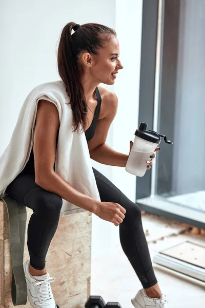 Ajuste mujer sosteniendo botella de plástico de agua después del entrenamiento — Foto de Stock