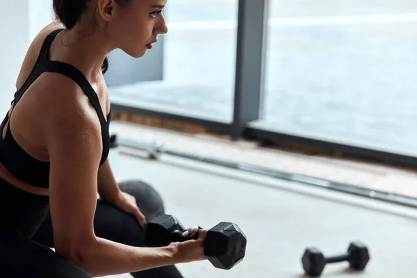 Jeune femme exerçant des poids de levage dans la salle de gym. Pompage des muscles des bras — Photo