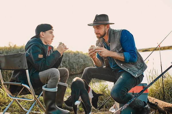 The first joint fishing of adult father and teen son in warm, sunny day. — Stock Image The first joint fishing of adult father and teen son in warm, sunny day. Stock Photo