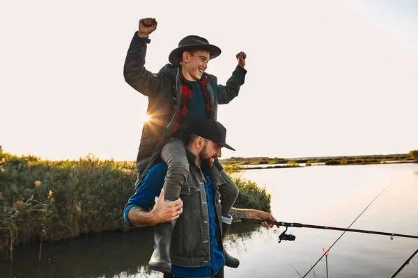 The first joint fishing of adult father and teen son in warm, sunny day. — Stock Image The first joint fishing of adult father and teen son in warm, sunny day. Stock Image