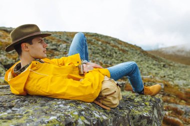 Elinde çay tutan ciddi bir adam.