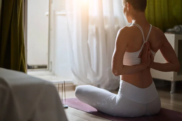 Back view of attractive short-haired girl in sportswear sitting on violet mat — Stock Photo, Image