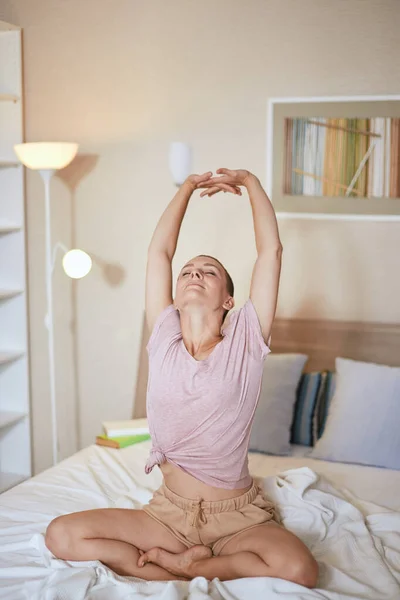 Beyaz kadın evde yatakta yoga yapıyor. — Stok fotoğraf