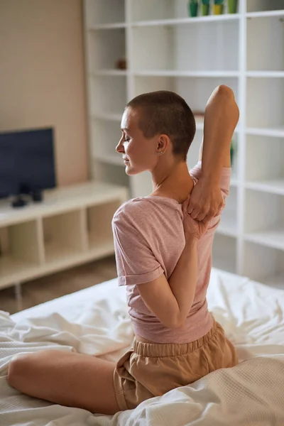 Närbild på kvinnan på sängen, armarna bakom ryggen — Stockfoto