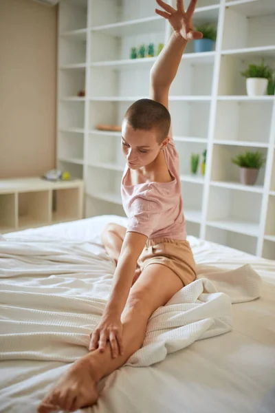 Joven mujer fitness en pijama haciendo ejercicios en casa en la cama. Estilo de vida saludable — Foto de Stock