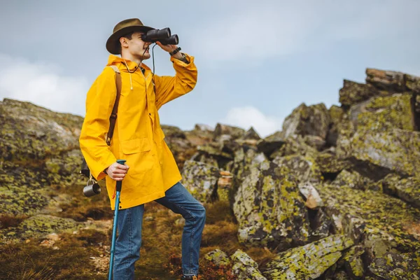 Mladý dobrodružný turista dosáhl vrcholu hor a dalekohledem — Stock fotografie