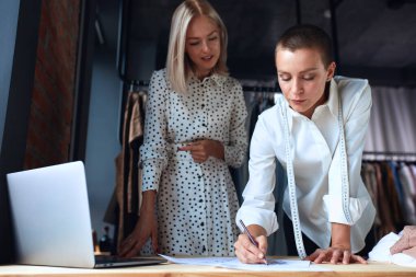 Güzel, keyifli genç bir kadın Talor 'la şık bir atölyede tartışıyor.