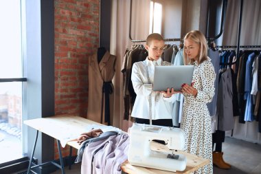 İki kadın dizüstü bilgisayara bakıyor. Model ve moda tasarımcısı