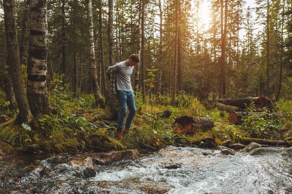 Giovane che si toglie i vestiti mentre si trova sulla riva del fiume — Foto Stock