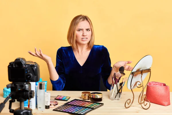 Displeased female cosmetics expert spreads hands, frowns face in dislike — Stock Photo, Image