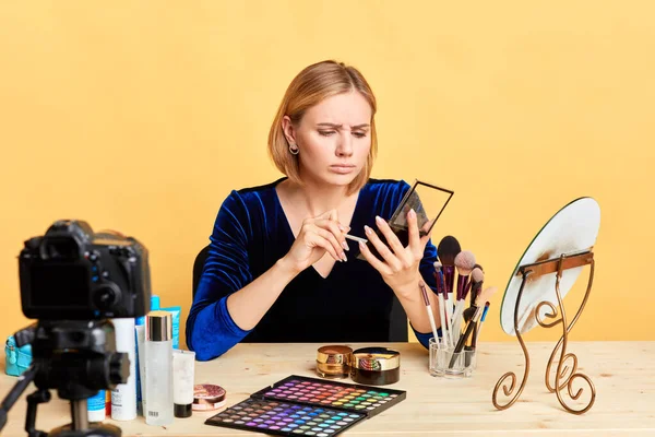 Smutny młody makijaż kobieta artysta posiada palety powiek, rozczarowany wyraz twarzy — Zdjęcie stockowe