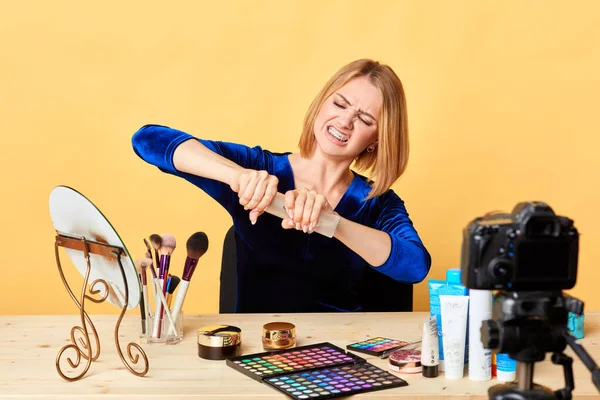 Irritated female makeup artist tries to open firmly closed bottle, clenches teeth — Stock Photo, Image