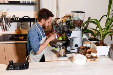 Kahve dükkanında kapuçino hazırlayan genç barista.