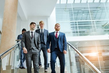 Smokinli iş adamları merdivenlerden aşağı iniyor.