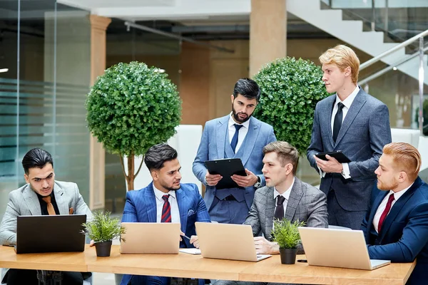 Équipe de jeunes entrepreneurs multinationaux assis sur la table — Photo