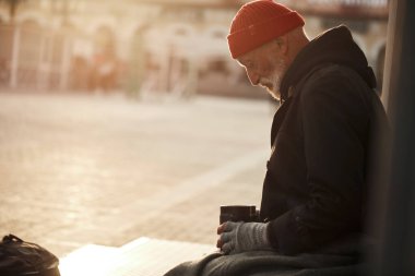 Şehrin göbeğinde oturan yaşlı evsiz adam para istiyor.