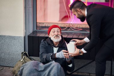 İş adamı dilenci erkeğe yardım eder