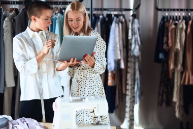 İki kadın dizüstü bilgisayara bakıyor. Model ve moda tasarımcısı