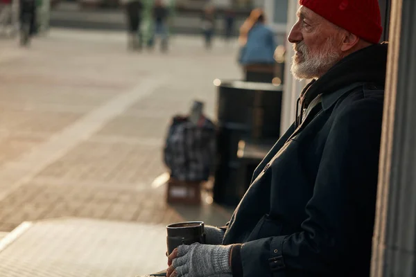 Hombre maduro sentado en el centro de la ciudad pidiendo dinero — Foto de Stock