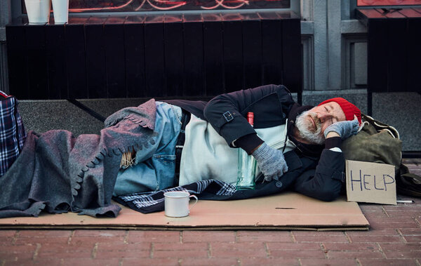 Нищий лежит на картонной коробке
