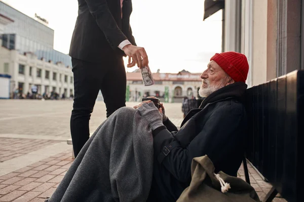 Hombre de negocios irreconocible ayuda a mendigo hombre sin hogar —  Fotos de Stock