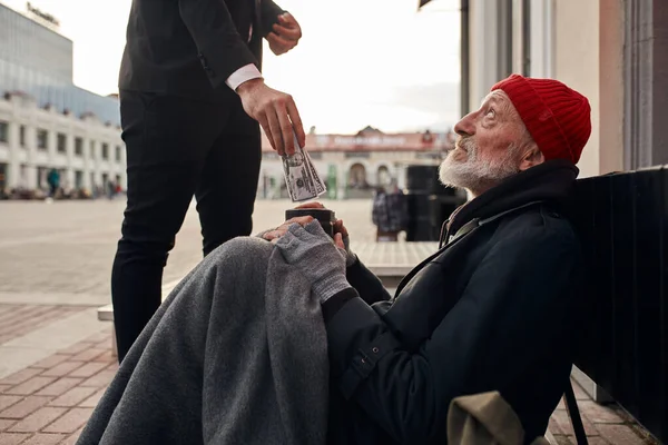 Hombre irreconocible en esmoquin donar dinero a personas sin hogar — Foto de Stock