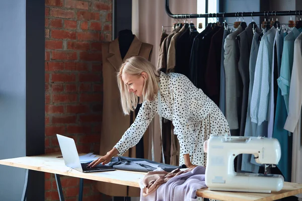 Mooie modeontwerper kijkt naar laptop en glimlach — Stockfoto