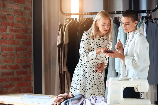 Look here. Young fashion designer and model look on telephone