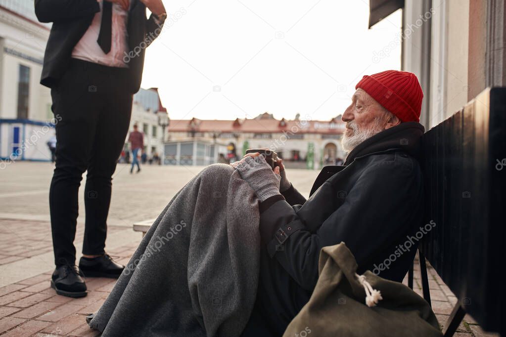 Unrecognizable business man help to beggar homeless man