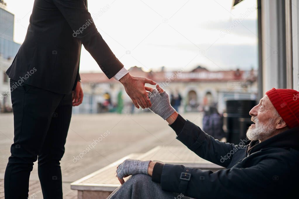 Businessman in suit hold out his hand to beggar man